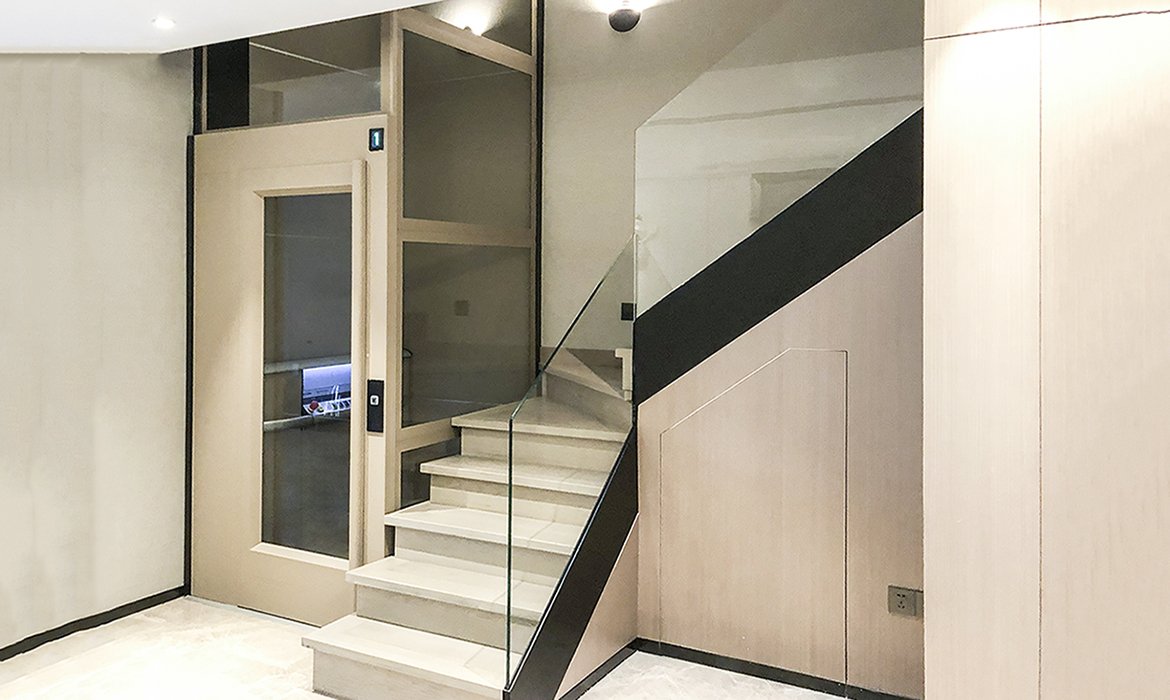 Glass lift in tinted glass placed inside staircase